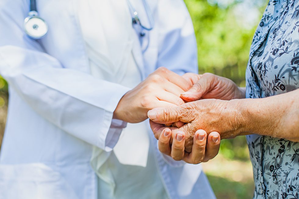 Close up medical doctor holding senior woman's hands.