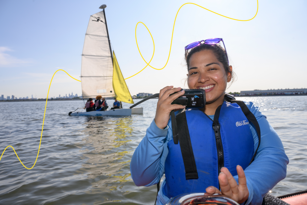 A woman captains a boat to monitor sailing students in the Long Island Sound.