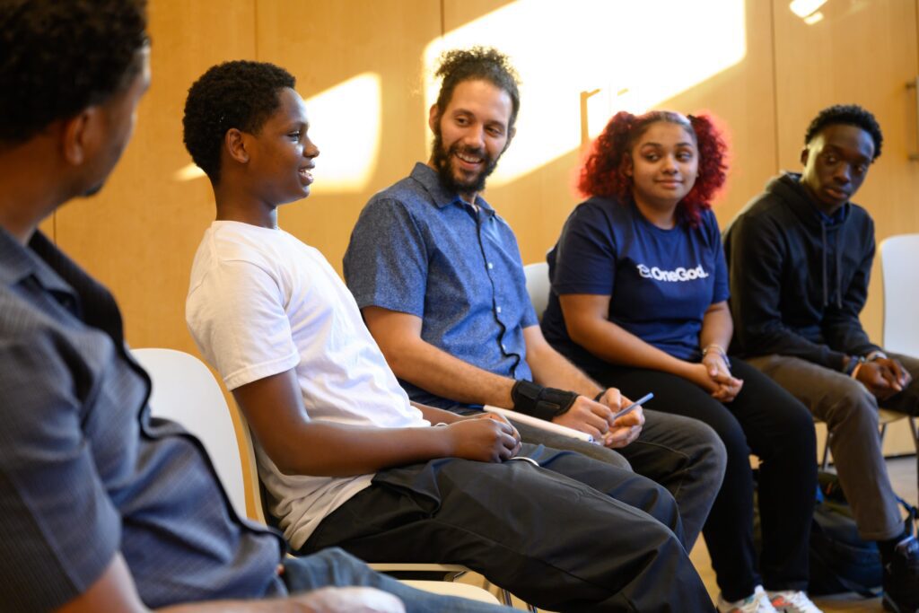 Young people sitting in chairs participate in group discussion.