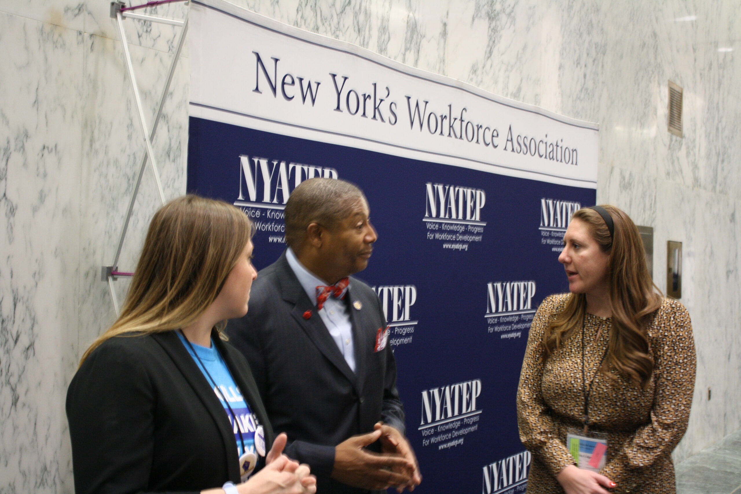 Three people speak at a meeting of New York’s Workforce Association.