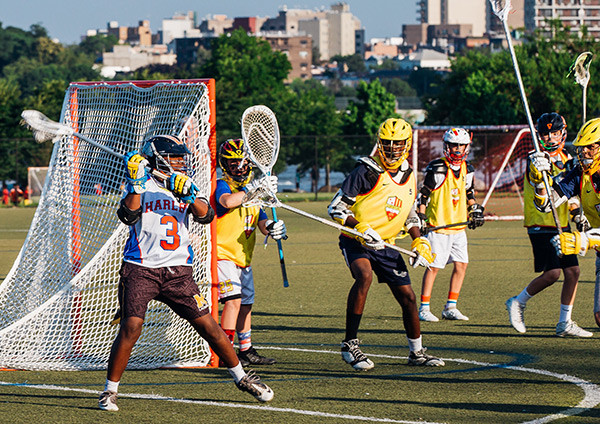Young athletes play lacrosse on a field.