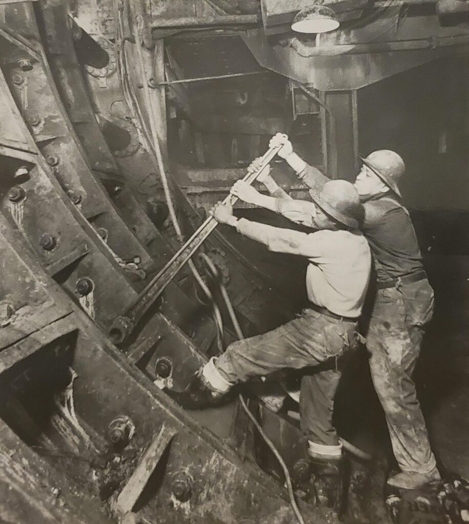 Two engineers turning a bolt with a long wrench.