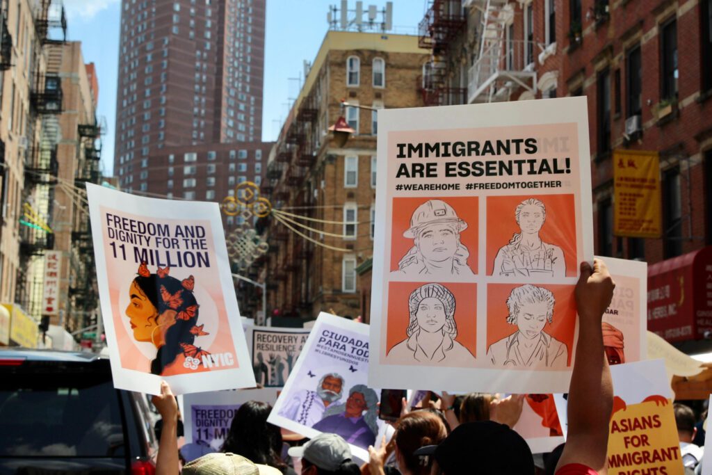 Protestors in the street holding signs in support of immigrant rights.