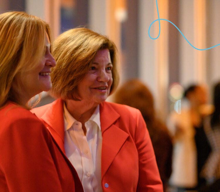 Two women mingle at an event.